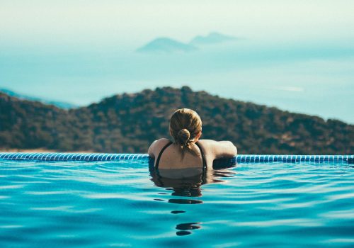 Young woman in infinity pool looking over mountains